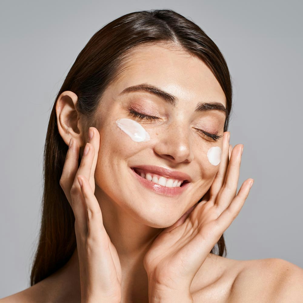 Woman smiling while applying lotion