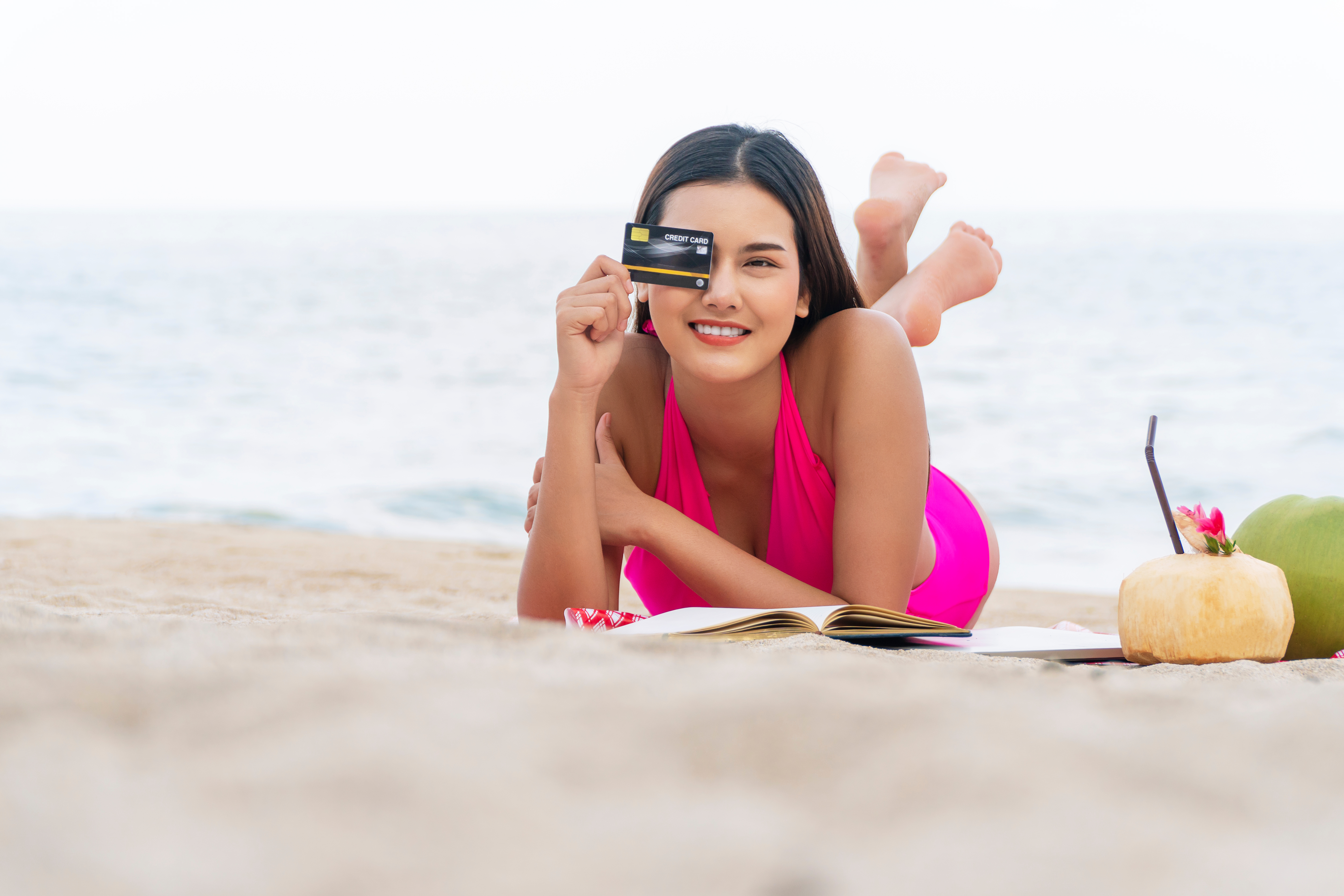 woman on beach holding credit card