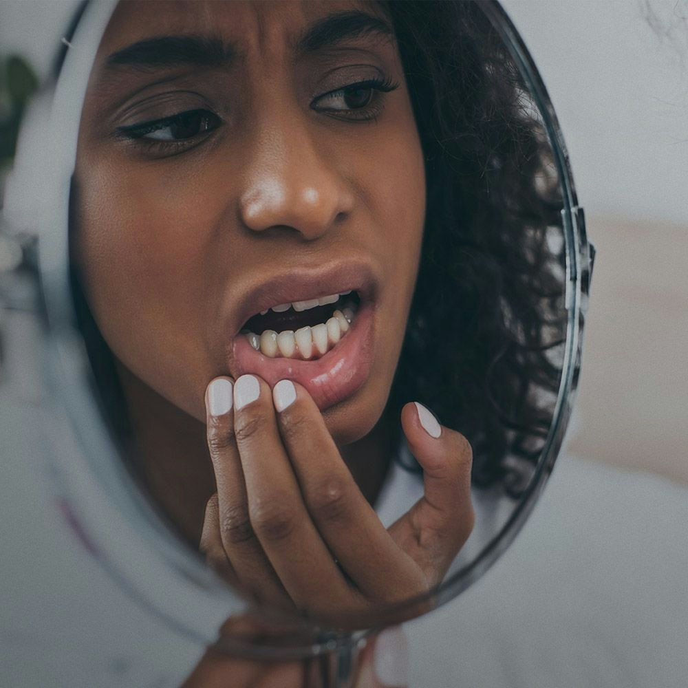 A woman examining her lower gum line