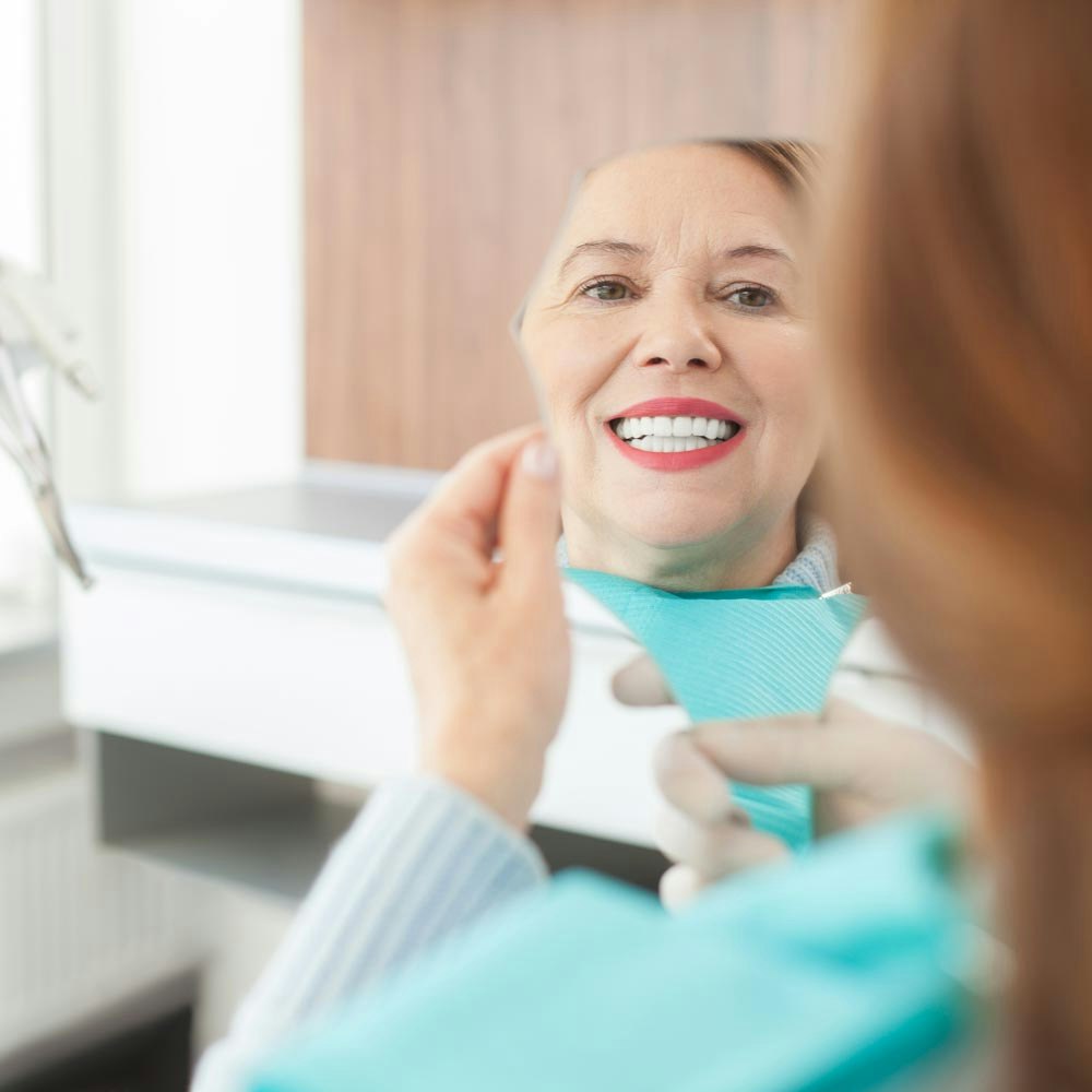 Woman viewing teeth in mirror
