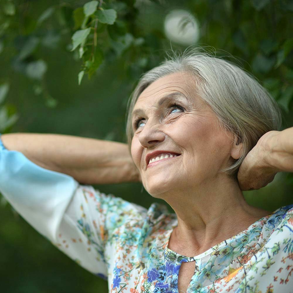 Older woman smiling with her hands clasped behind her head