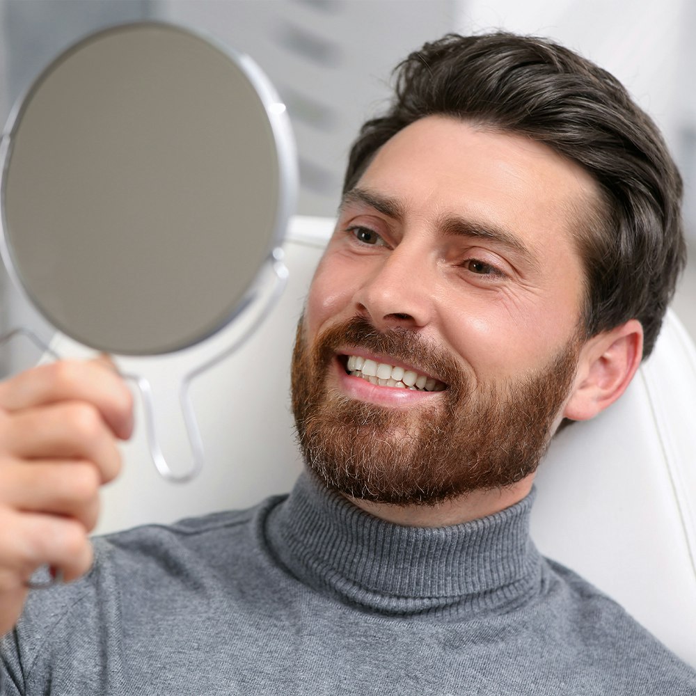 man looking in mirror at dentist