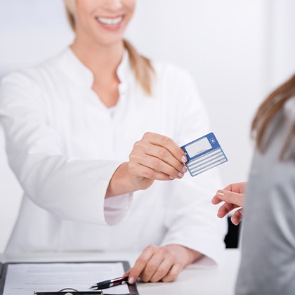 Smiling woman handing over credit card after BOTOX treatment