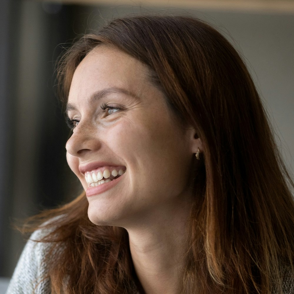 Woman smiling into a mirror after BOTOX treatment