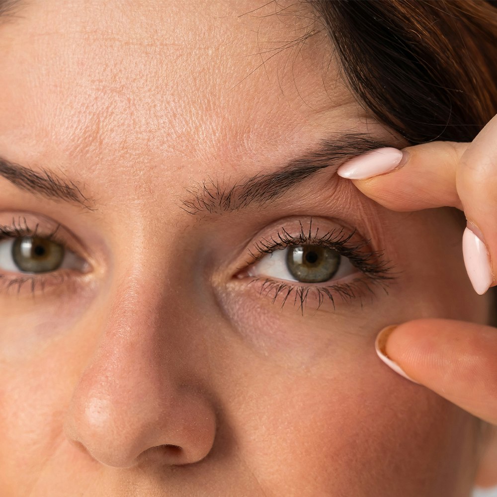 a woman using her fingers to lift her eyelids