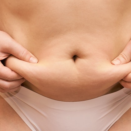 person pinching their stomach