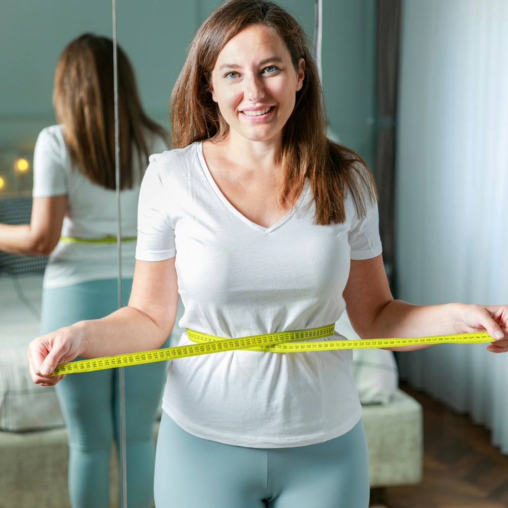 Woman smiling while measuring her waist