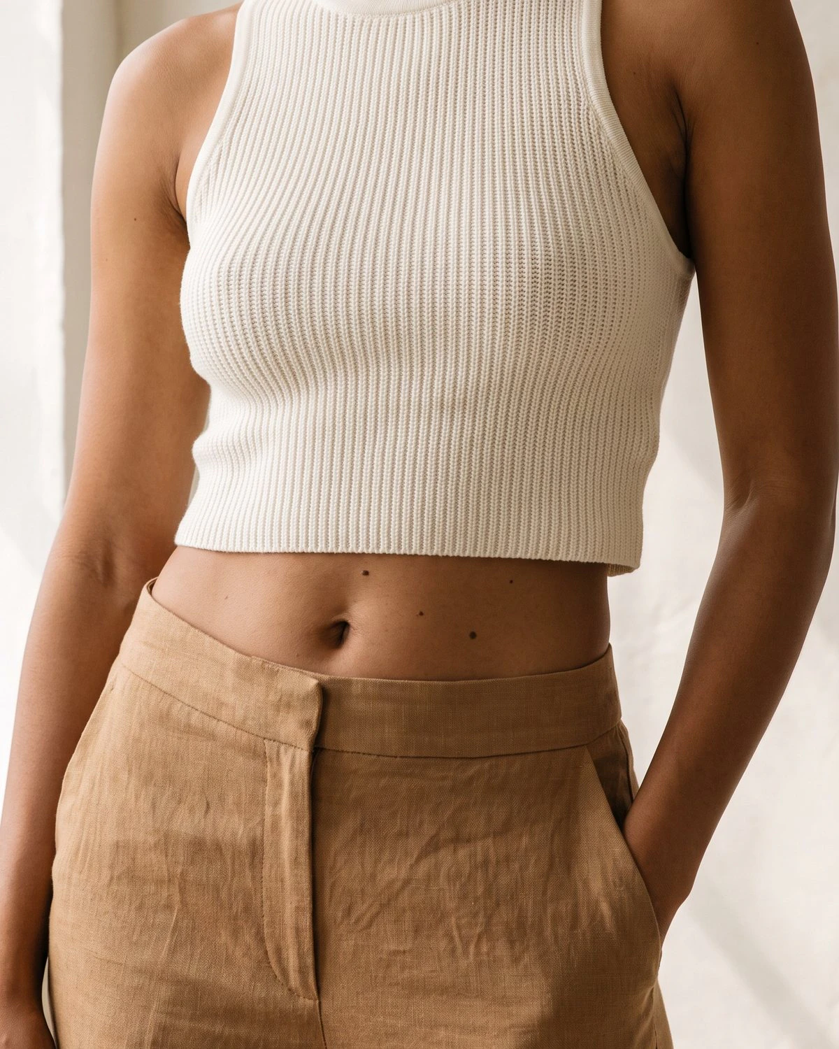 Torso of a woman in an ivory knit top and camel trousers, with the TUBA implant path drawn from the belly button up to each breast