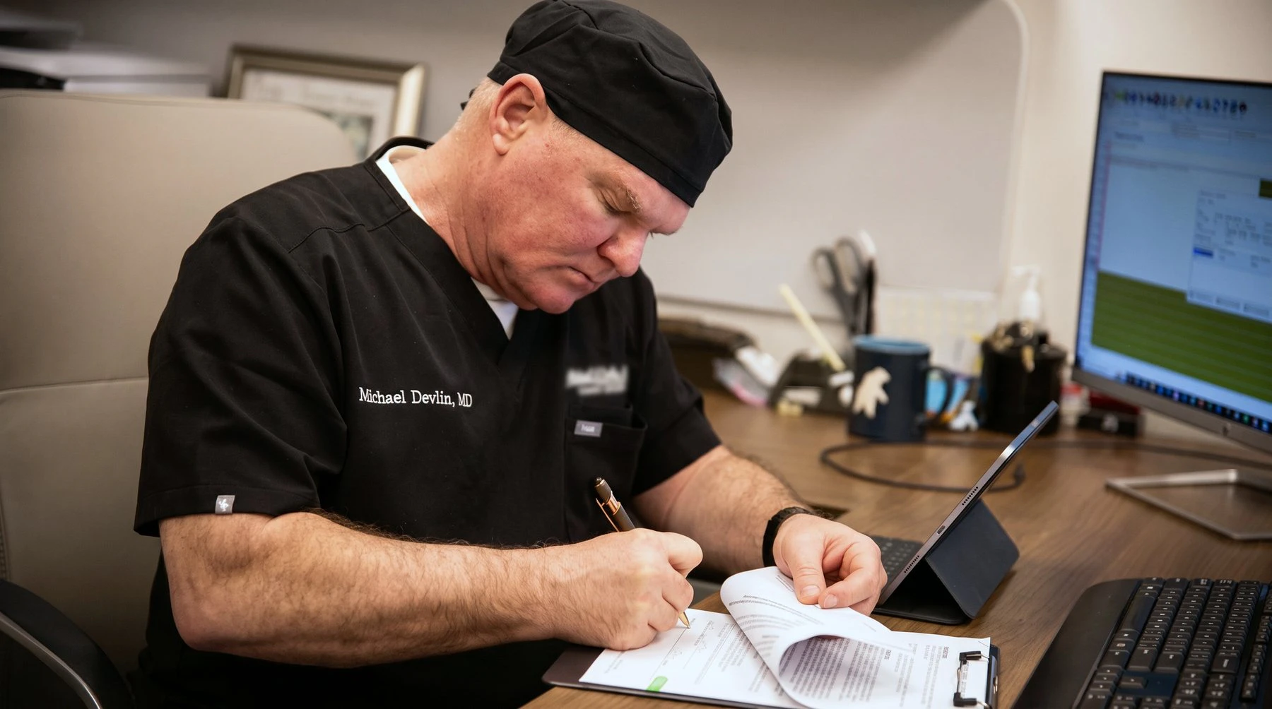Dr. Michael Devlin writing notes at his desk in his Little Rock office