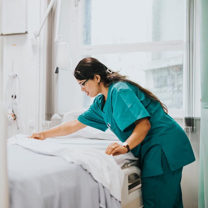hospital staff member making a bed