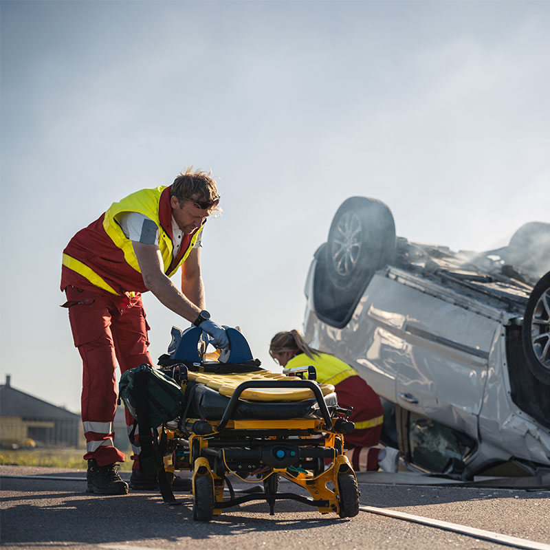 Man bringing stretcher toward scene of an accident