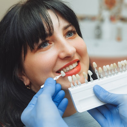 patient in dentist chair getting their shade of tooth matched