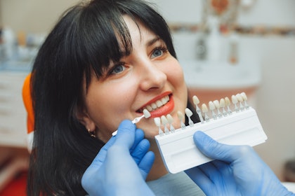 patient in dentist chair getting their shade of tooth matched