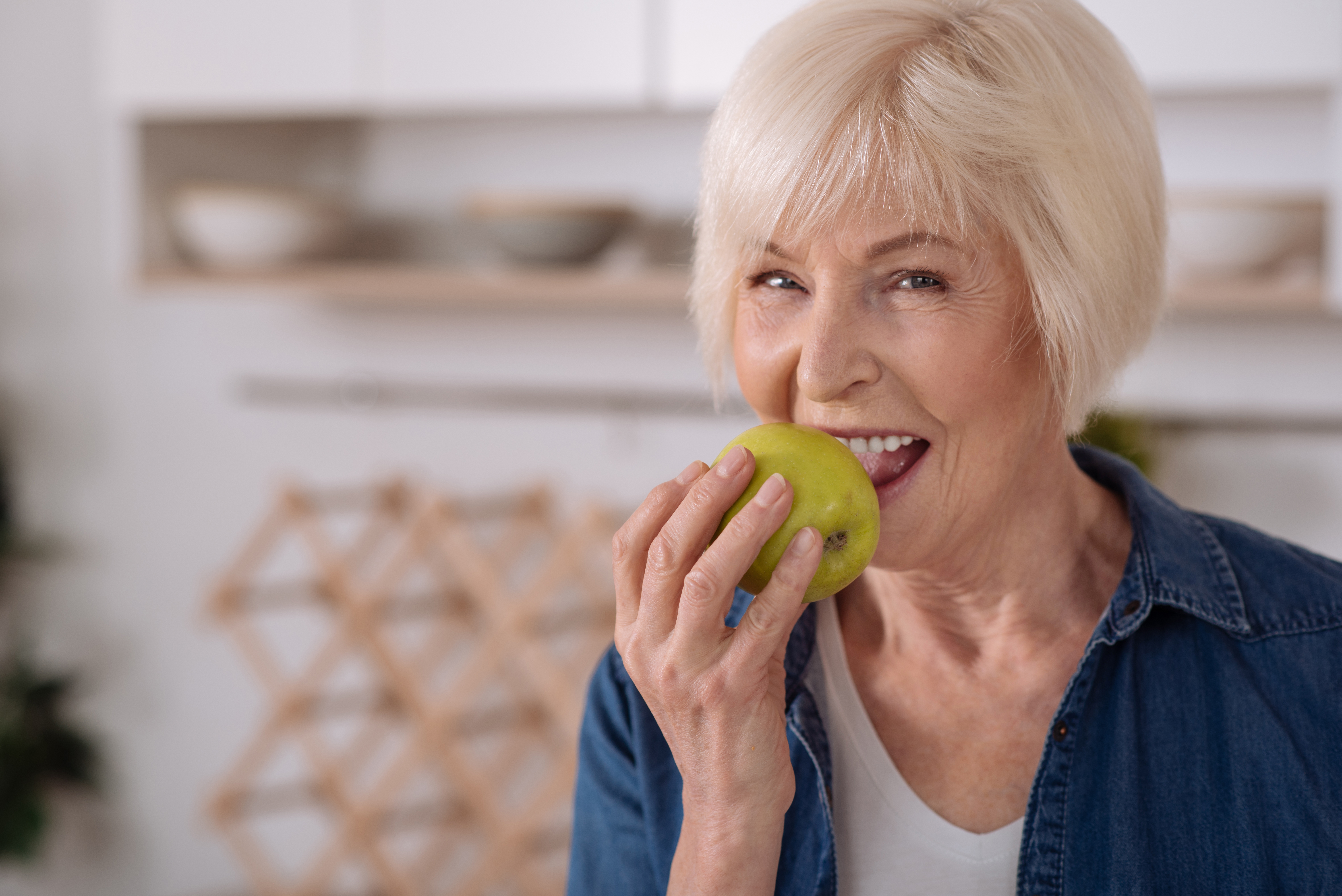 woman smiling while biting into an apple