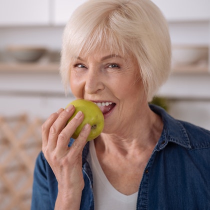 woman smiling while biting into an apple