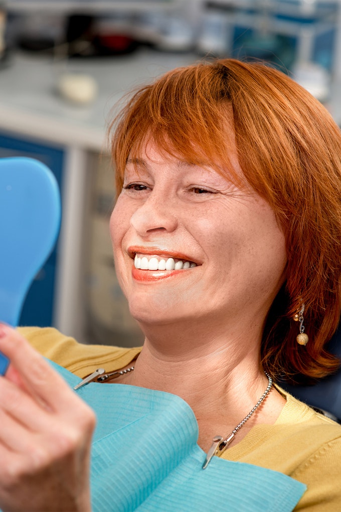 a woman looking at her teeth in a mirror