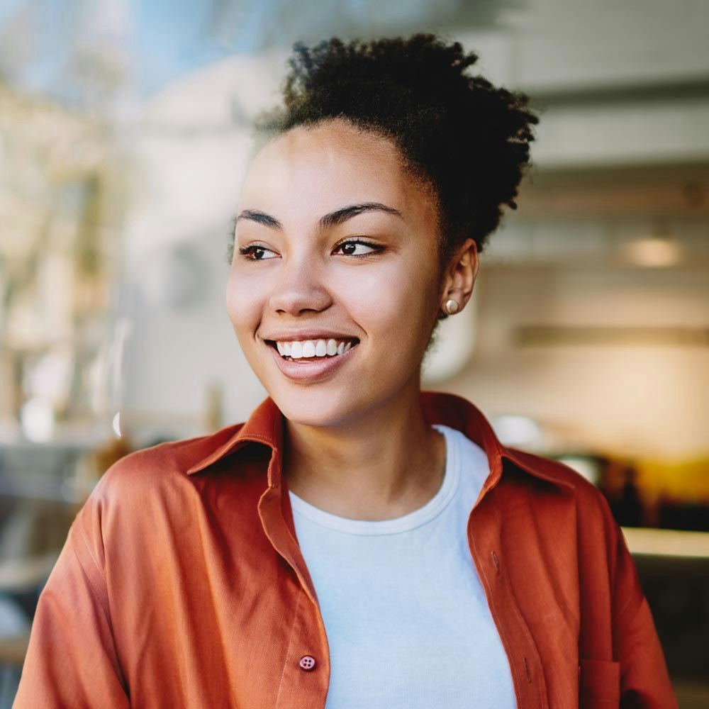 Young woman smiling while looking outside a cafe window