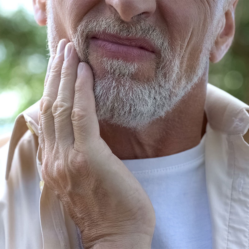 Elderly man rubbing his jaw in pain