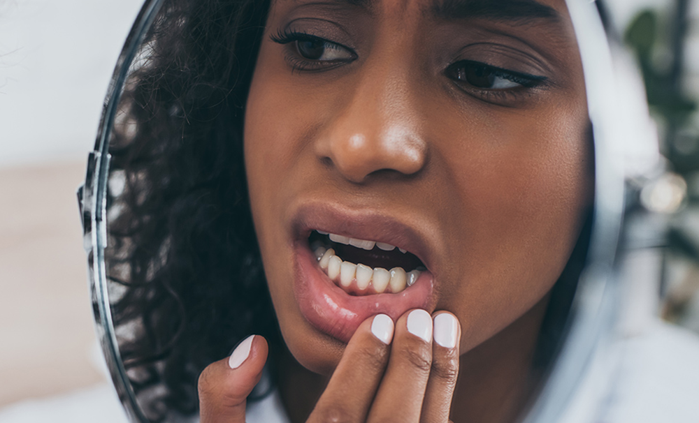 New Jersey woman looking at damaged tooth in the mirror