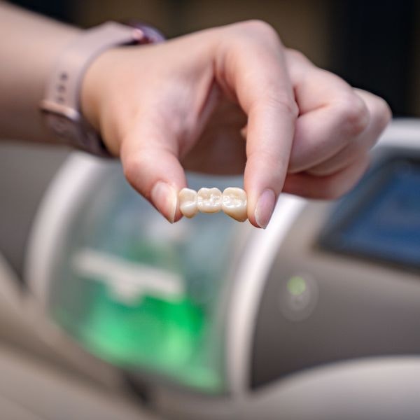 Person holding dental bridge