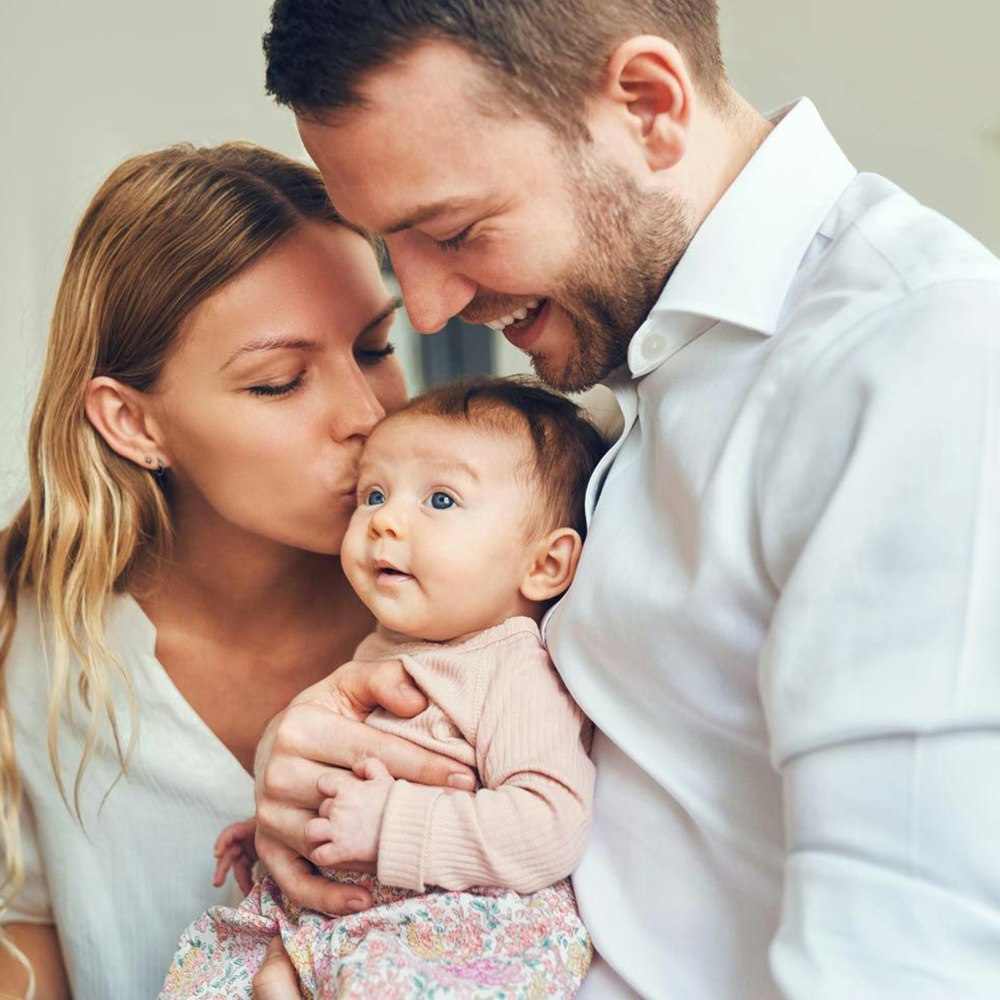 Man and woman kissing baby
