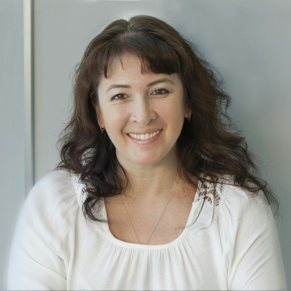 brunette woman smiling against a light blue background
