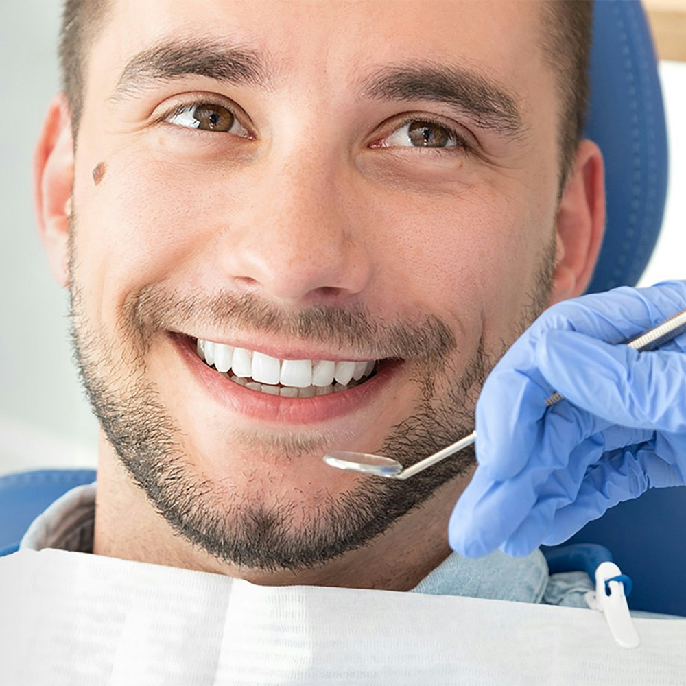 Man smiling in dental chair during cleaning and exam