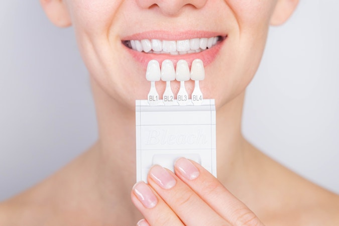 Woman holding veneer shade guide next to her teeth