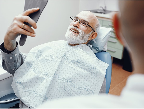 man looking at teeth in mirror