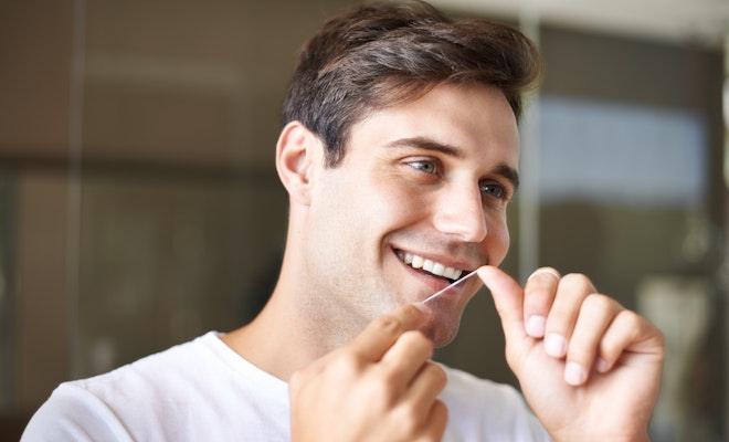 Young man flossing in the mirror
