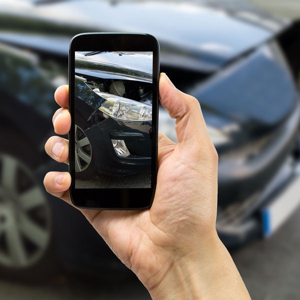 Taking cellphone photo of damage to car after an accident