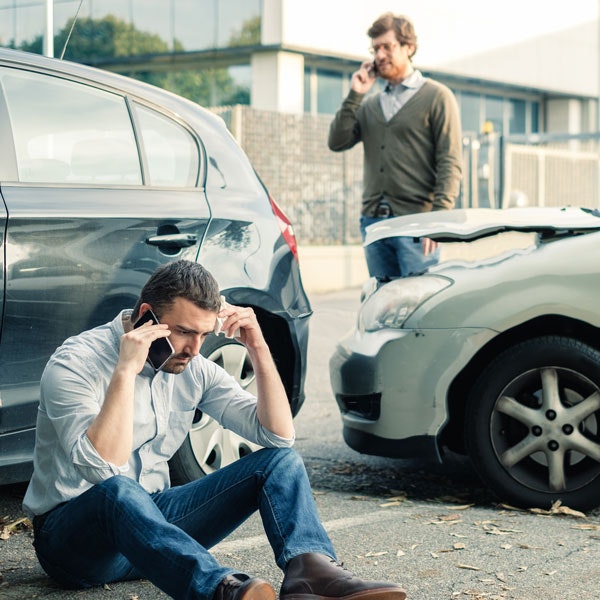 Two people on their cellphones after a rear-end accident
