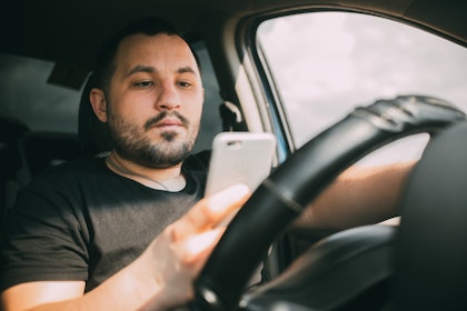 Man looking at phone while driving