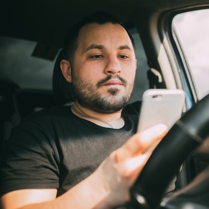 Man looking at phone while driving