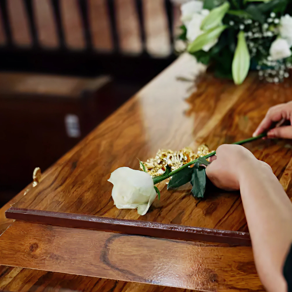 Woman placing rose on casket