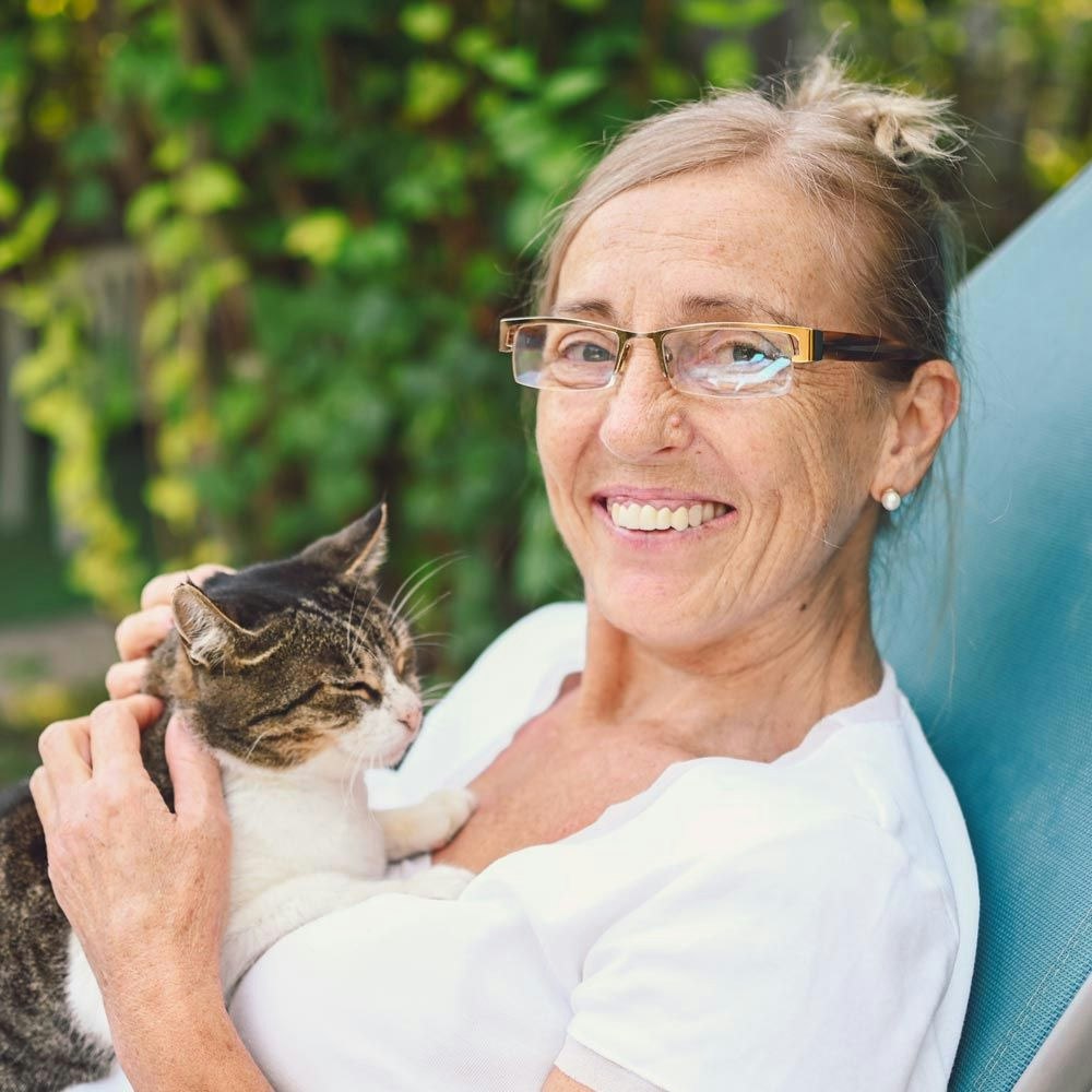 Woman holding her cat and smiling with new dental implants