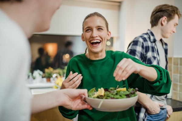 Smiling woman squeezing lemon onto salad