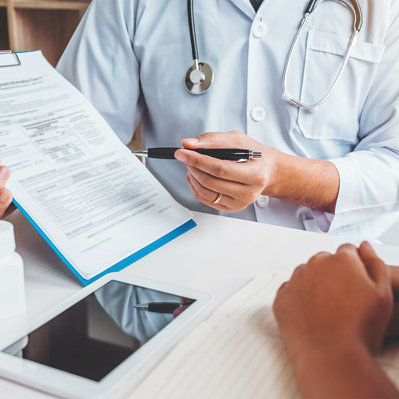 Doctor holding up clipboard and documentation to patient