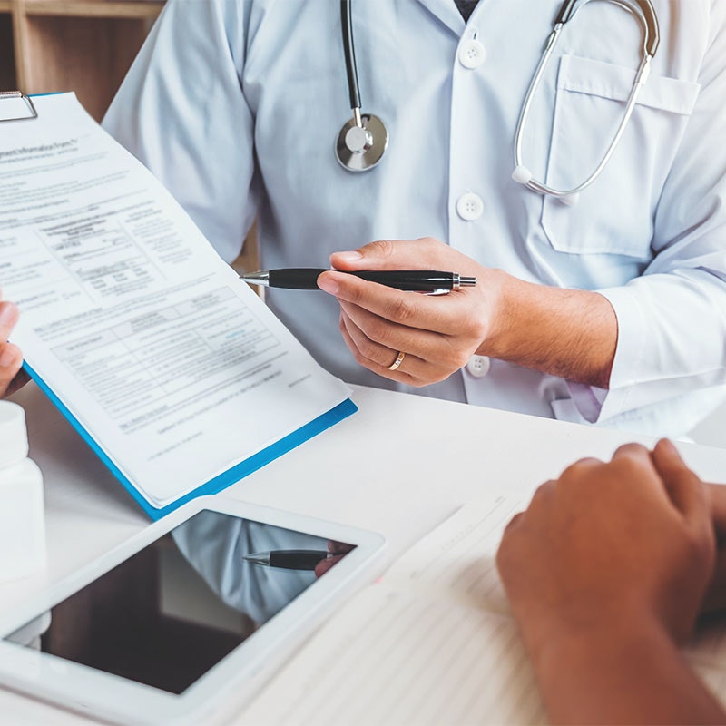 Doctor holding up clipboard and documentation to patient