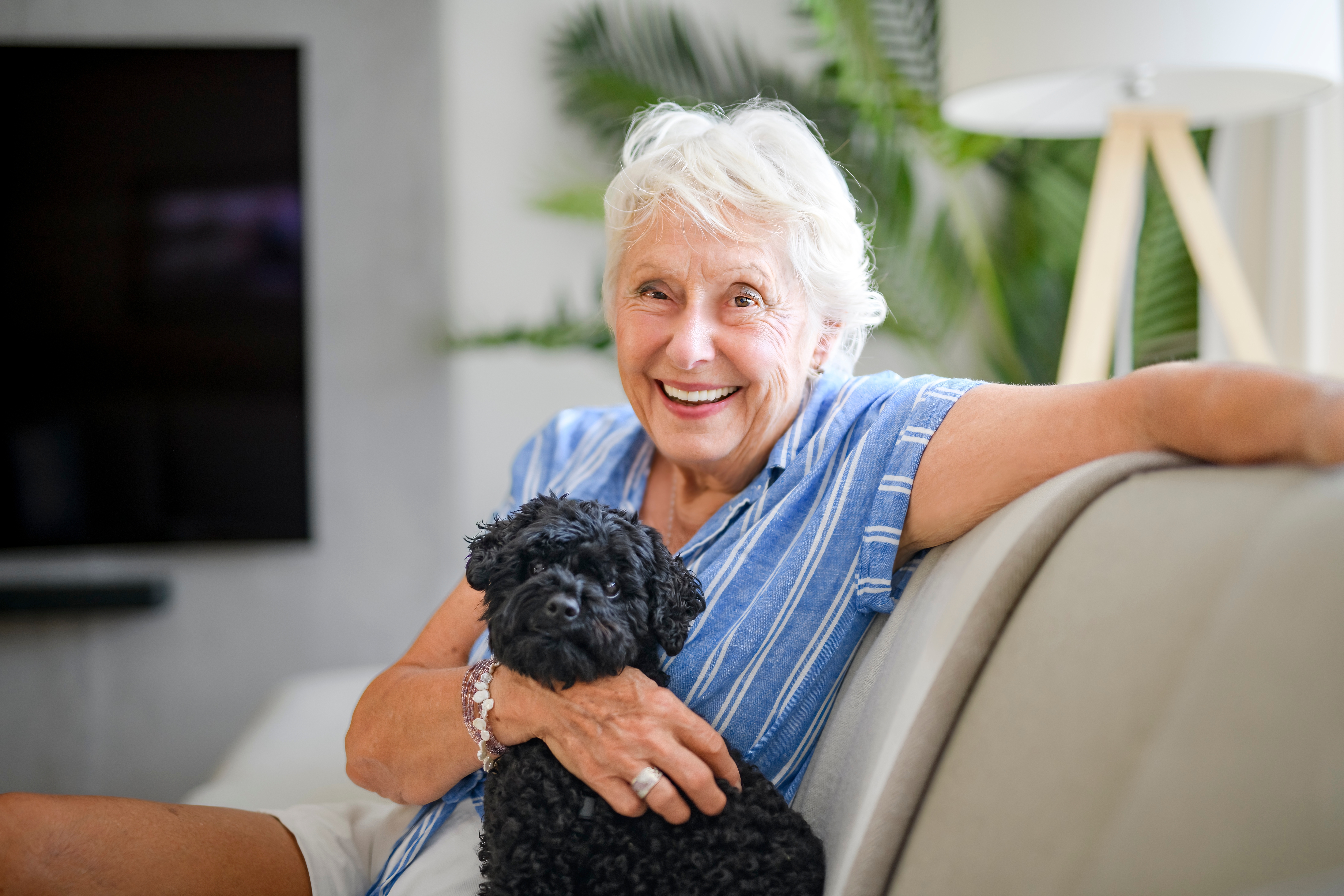 Senior woman smiling on couch with dog