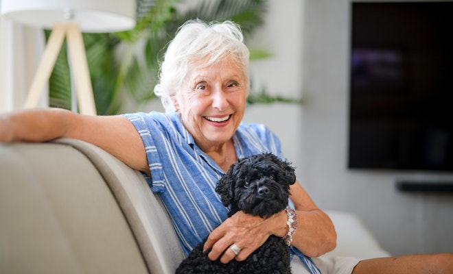 Senior woman smiling on couch with dog