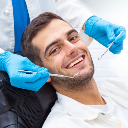 man at dentist appointment with cleaning tools