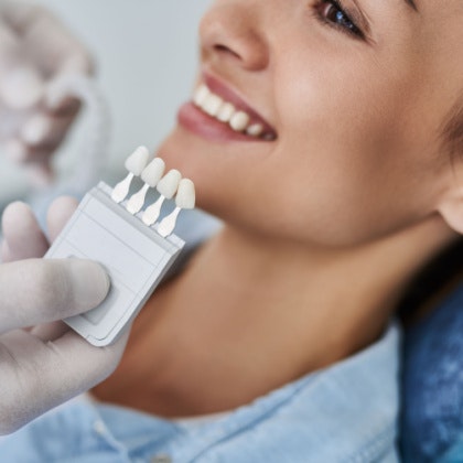 woman with veneers held in front of face