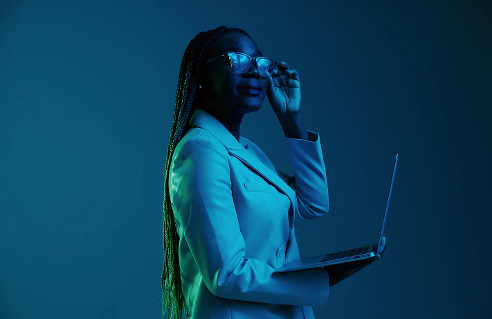 Woman smiling with sunglasses holding a laptop