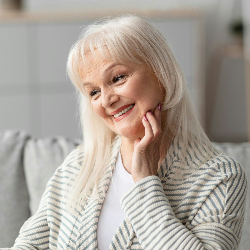 Mature woman admiring full mouth reconstruction in mirror