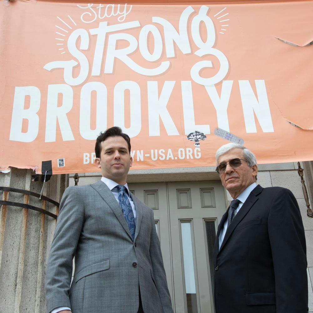 Lawyers Zucker & Regev in front of "Stay Strong, Brooklyn" signage