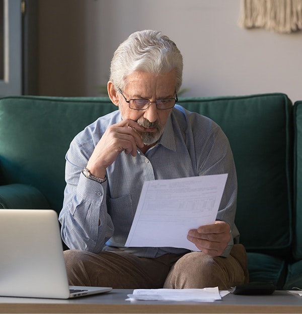 Suspicious elderly man looking at financial statements