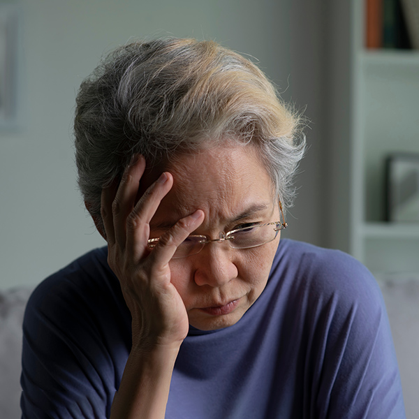 Upset elderly woman with head in hands