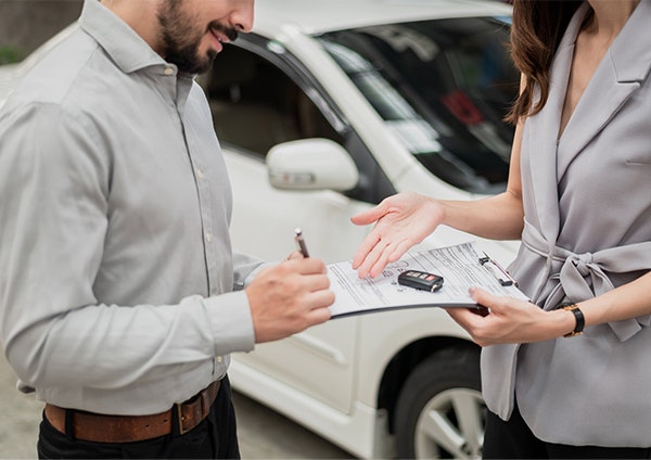 Man signing paperwork with car keys