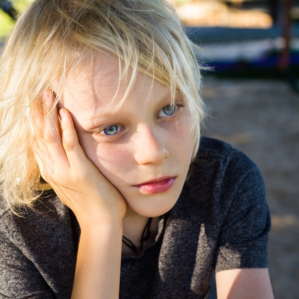 sad child sitting near a playground